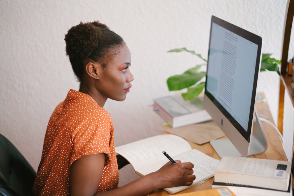 A woman reading from a computer and taking notes